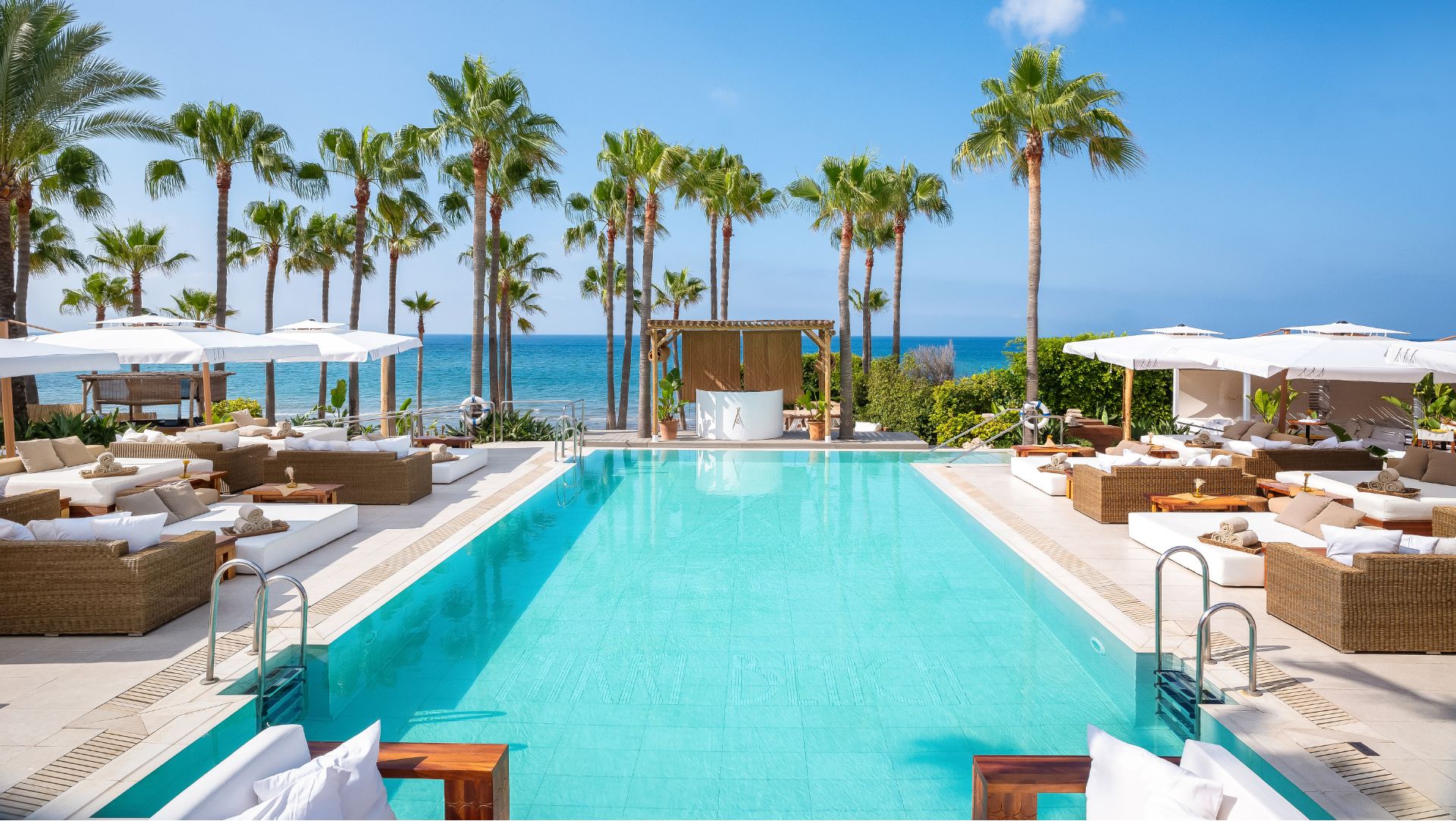 Party scene at Nikki Beach with DJ booth and people dancing.